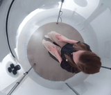 Woman sitting inside of a seated chamber, portable hyperbaric chamber